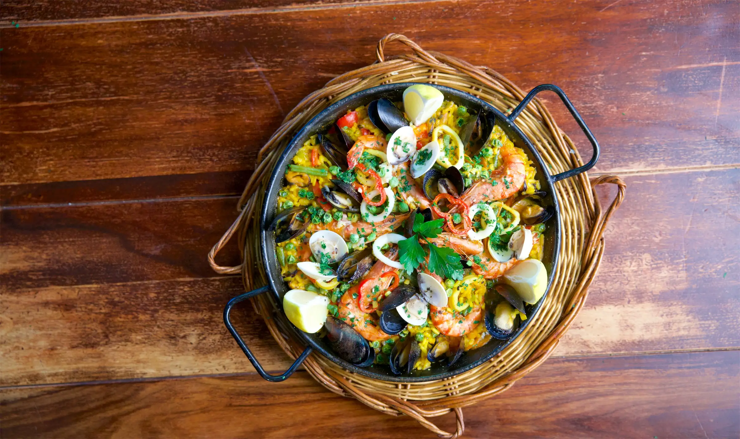 Paella in der Pfanne von oben, auf dem Holztisch im Lokal